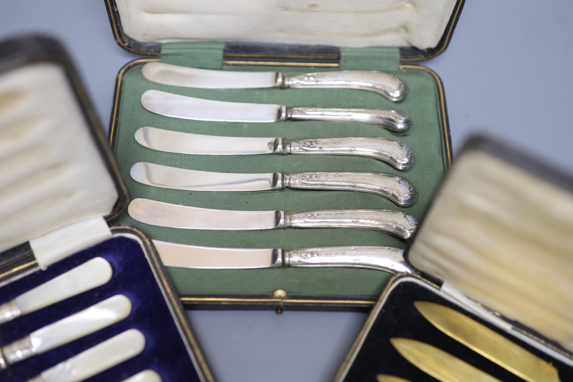 A cased set of six silver pistol handles tea knives(a.f.) and two other cased sets of knives.